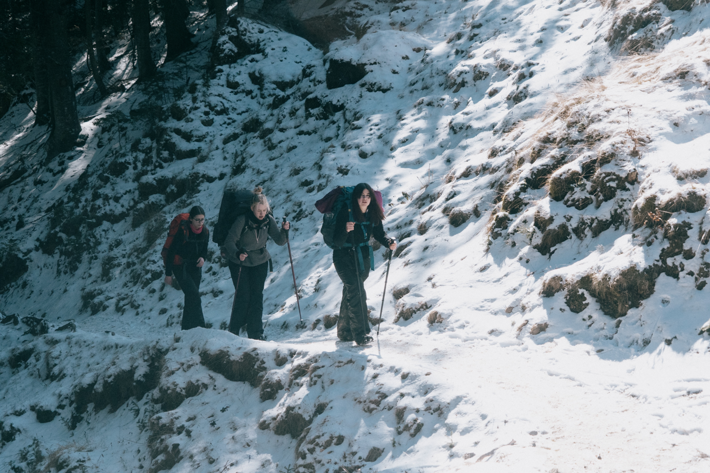 Trei cercetasi mergand pe un drum de munte inzapezit